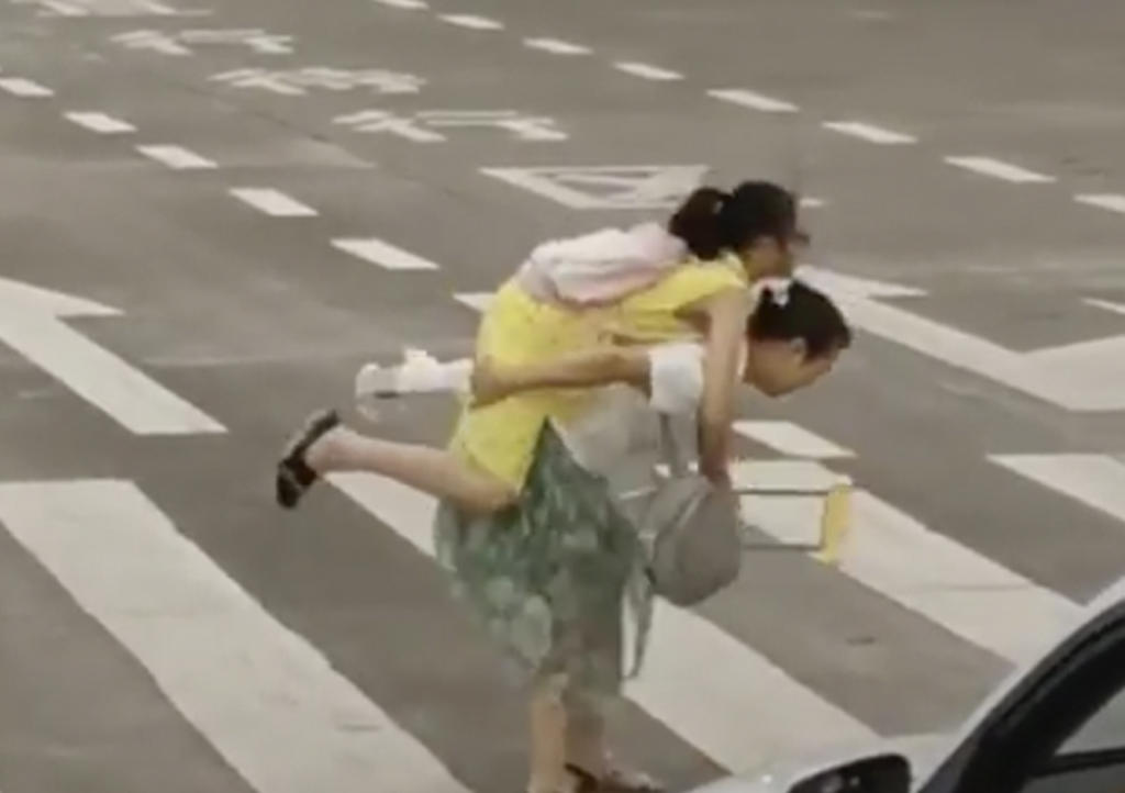 Carga a niña en muletas para ayudarla a cruzar la calle