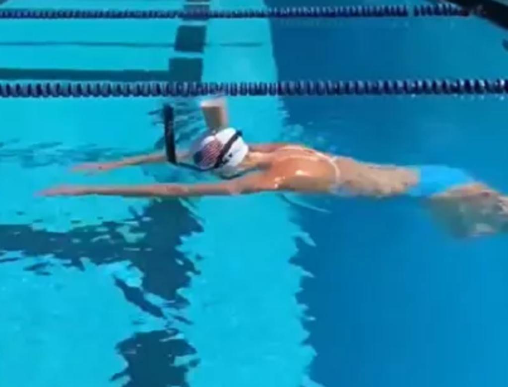 Atleta olímpica nada mientras balancea un vaso de leche en su cabeza