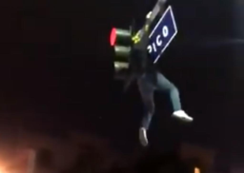 Hombre salta hacia una multitud desde un semáforo durante celebración pública