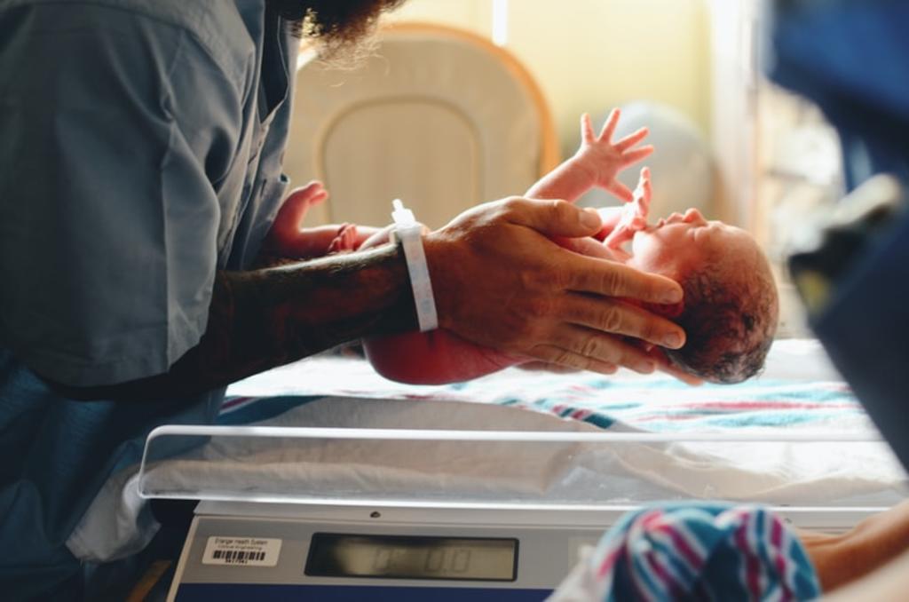 Bebé 'nace harto del COVID'; arranca cubrebocas de médico