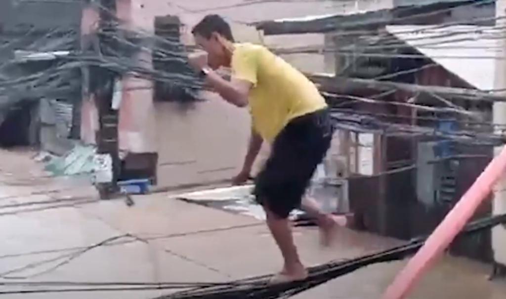 Hombre cruza calle inundada a través de cables de electricidad para pedir comida