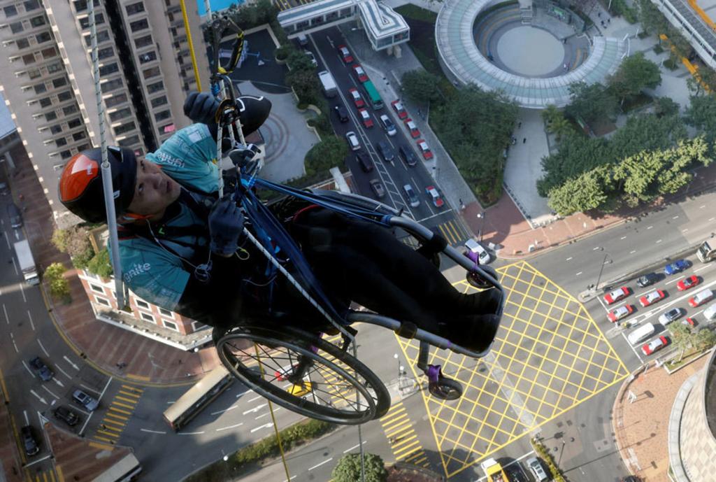 Alpinista en silla de ruedas escala un rascacielos en Hong Kong