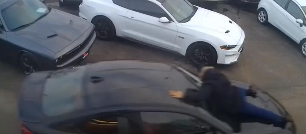 Vendedor de autos cuelga desde el capó de un vehículo para evitar que se lo roben