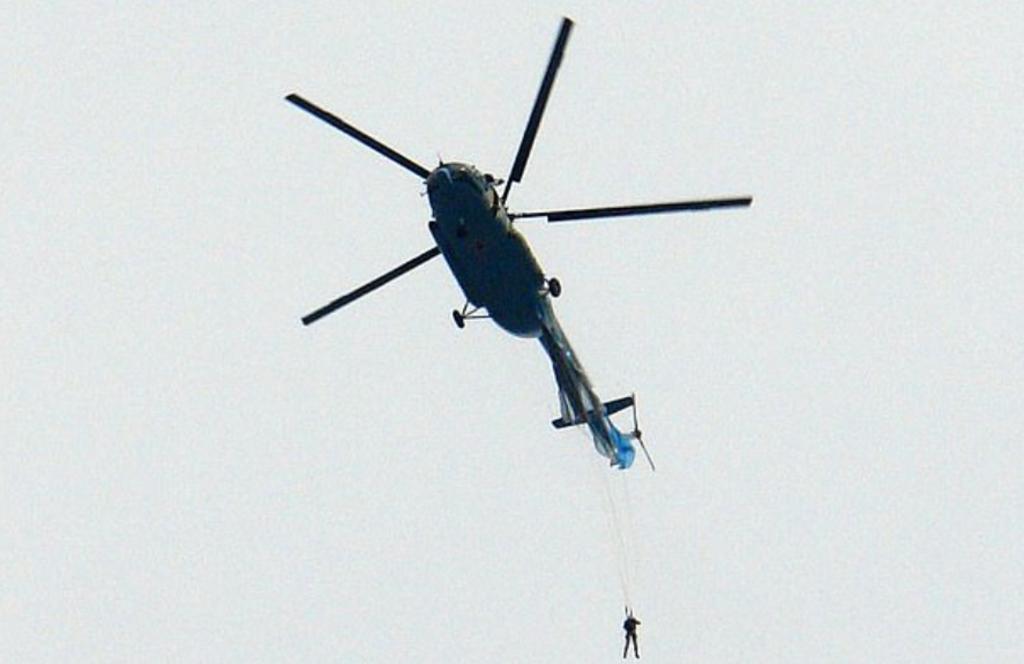Soldado ruso queda colgando desde un helicóptero porque su paracaídas se atoró al saltar