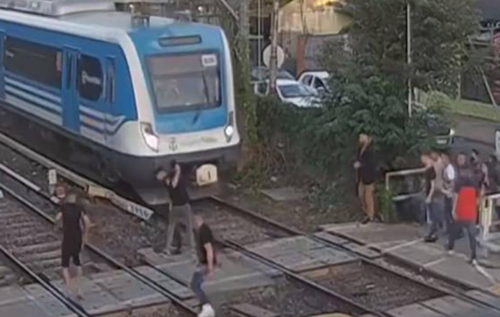 Jóvenes pelean sobre una vía férrea y por poco son embestidos por un tren