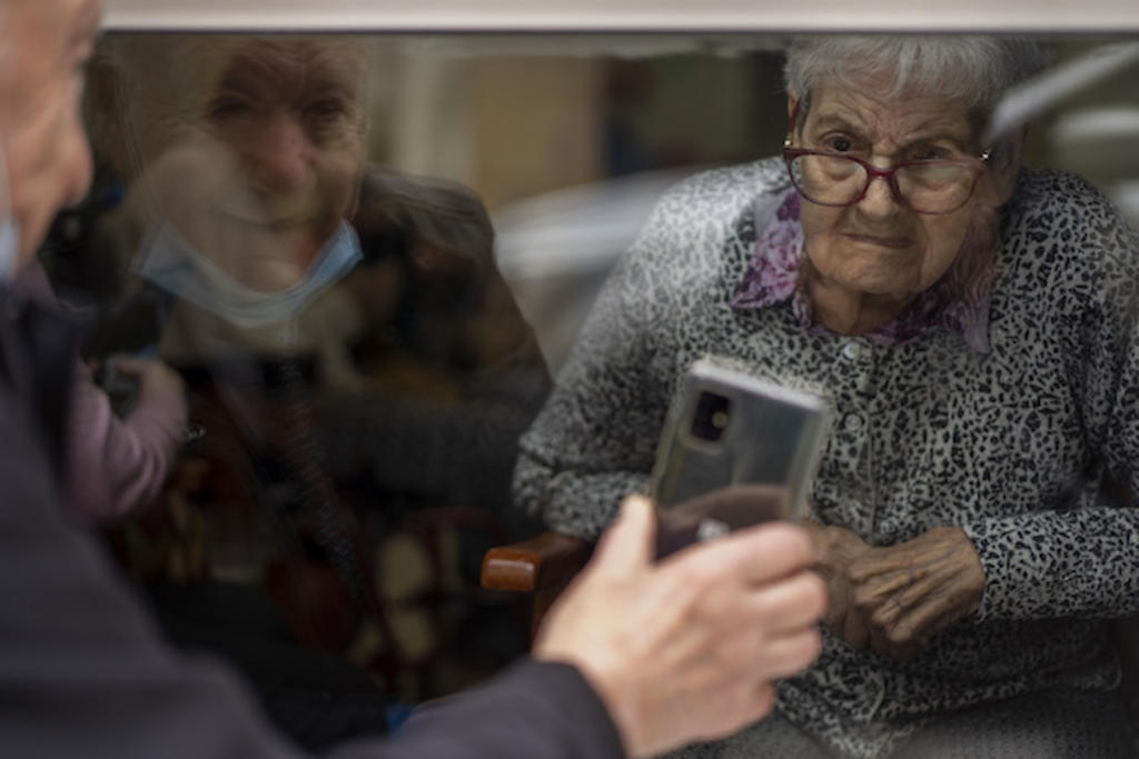 Pareja de ancianos se ve a través de un cristal por el COVID en España