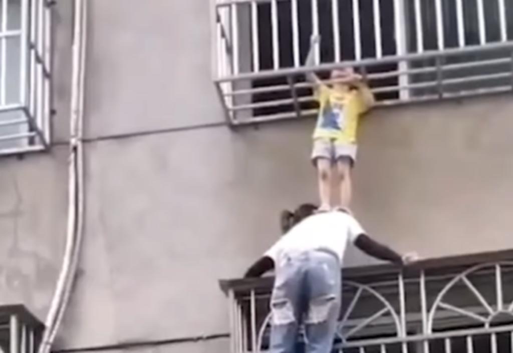 Mujer sostiene a niña que colgada desde una ventana en un tercer piso