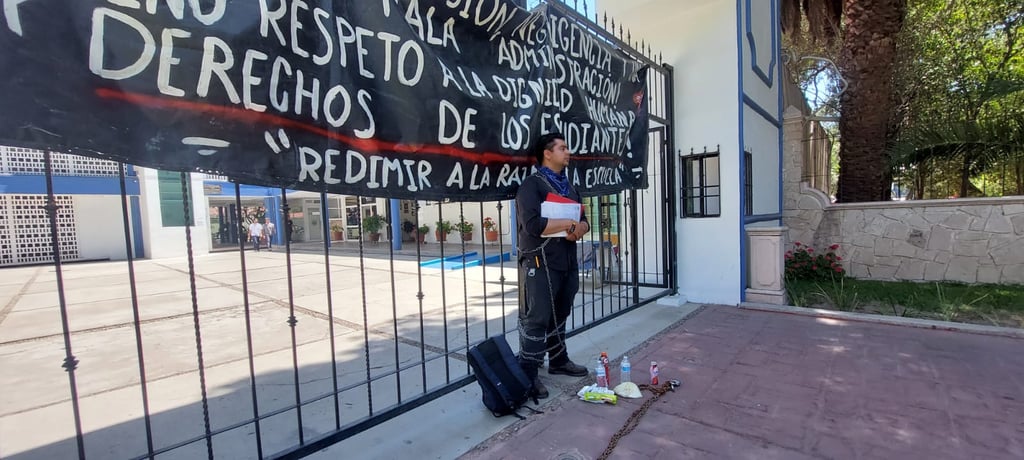 Joven se encadena en acceso a la Escuela Normal de Durango; exige restablecimiento de sus derechos