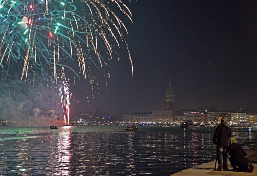 Varias personas observan los fuegos artificiales sobre la plaza de San Marcos para celebrar el Año Nuevo en Venecia