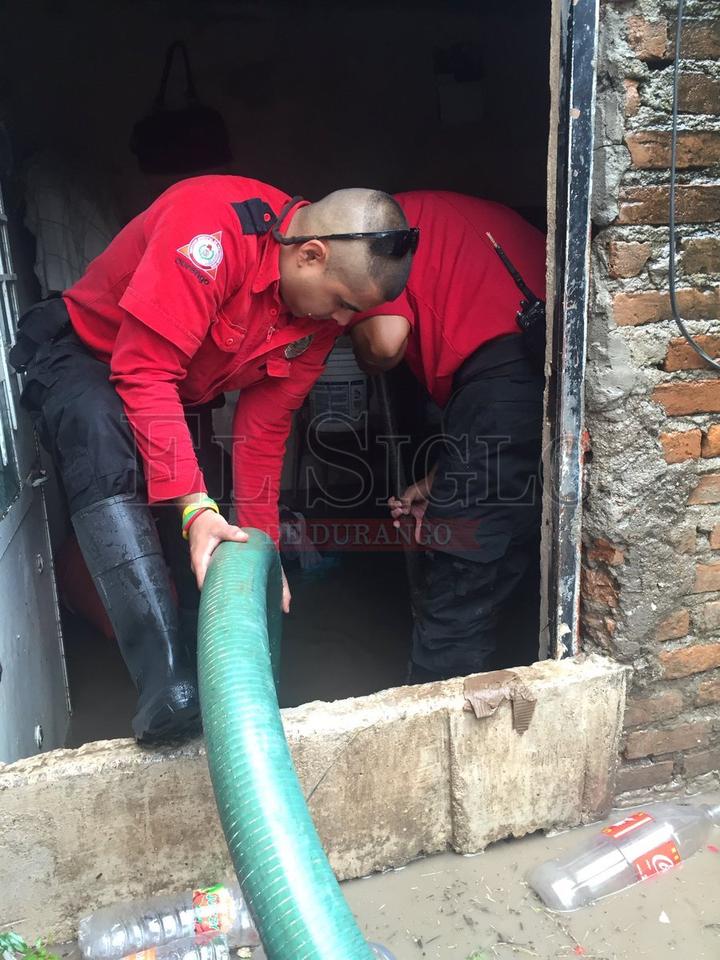 Elementos de Protección Civil ayudan a sacar el agua de las viviendas afectadas.