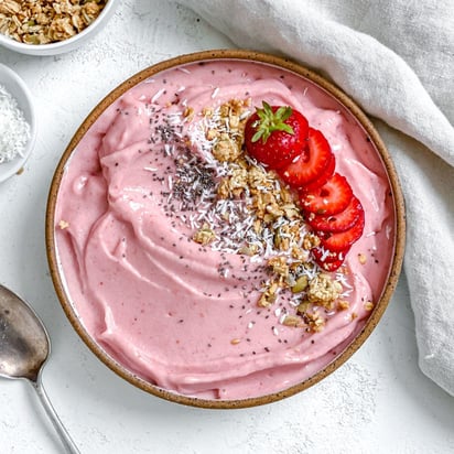 Prepara un smoothie bowl con yogur natural, plátanos y fresas frescas. Agrega muesli.