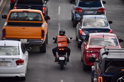 Acortando paso. Los motociclistas que trabajan en servicios de reparto circulan entre carros para llegar más rápido a su destino.
