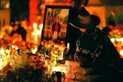Entre velas y flores de cempasúchil, las familias de Tzintzuntzan iluminan las tumbas de sus seres queridos durante la Noche de Muertos.