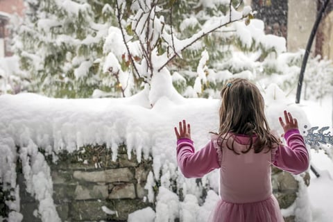 Una ni&ntilde;a mira por la ventana en la nieve larga espera en Bramois, cerca de Sion, Suiza.