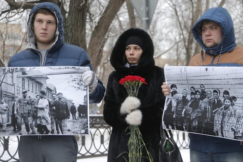 Tres jóvenes muestran fotografías y flores durante una protesta ante la embajada polaca en Moscú, la protesta estaba dirigida al ministro polaco de Exteriores, Grzegorz Schetyna, quien dijo que fueron los soldados ucranianos los que liberaron Auschwitz el 27 de enero de 1945.