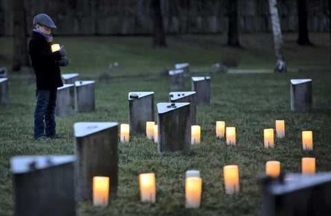 Un niño enciende una vela durante la celebración del Día Internacional de Conmemoración en Memoria del Holocausto en el cementerio judío cercano al campo de concentración de Terezin, República Checa.