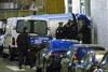 Unos policías vigilan mientras los cadáveres de las víctimas del ataque a la sede del semanario satírico "Charlie Hebdo" en París, Francia, son introducidos en un furgón.