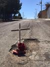 También hay una imagen en la que aparece una cruz, adornada con flores, semejando una tumba en medio de un bache de considerables dimensiones.