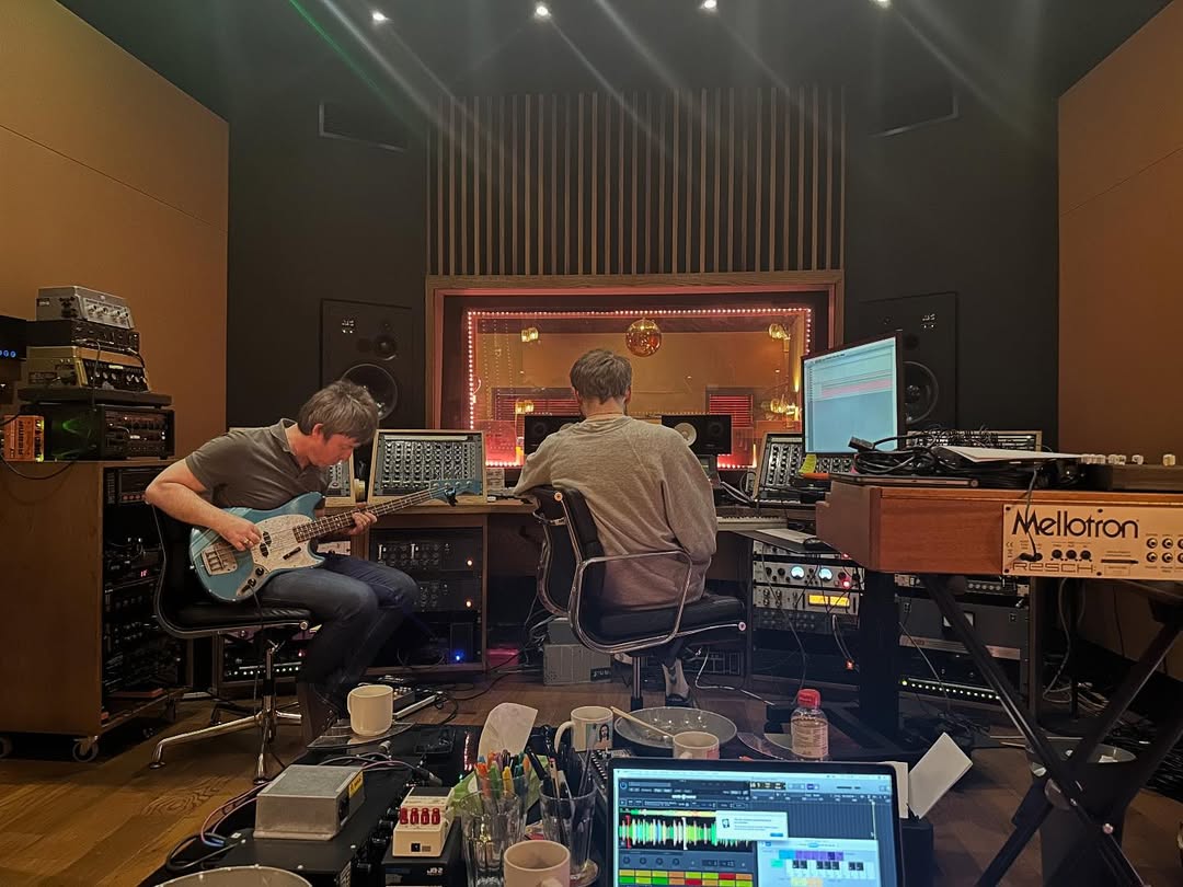 Otra de las fotos muestra a Noel Gallagher tocando un Fender Bronco Bass color turquesa, junto con una línea de grabación, la cual parece estar ya terminada.